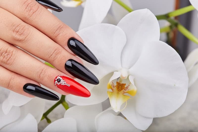 Long Oval Nails In Black Red Polish With A Gemstone Design